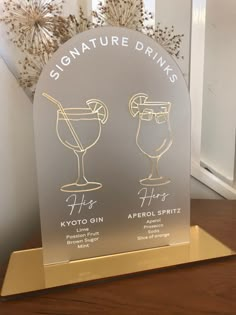 a sign that says signature drinks and two glasses with lemons in them on a wooden table