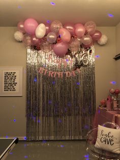 balloons and streamers are hanging from the ceiling in front of a birthday party backdrop