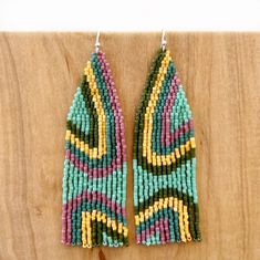 two pairs of beaded earrings on top of a wooden table