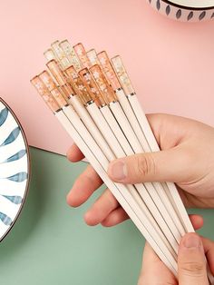 the person is holding six chopsticks in their hand and they are next to a plate