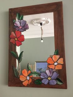 a mirror with flowers painted on it and a light fixture in the corner behind it