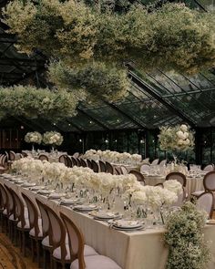 a long table is set with white flowers and greenery for an elegant wedding reception