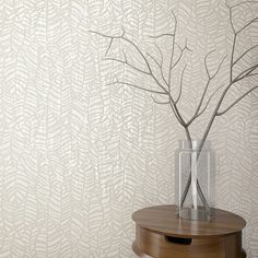 a vase with some branches in it sitting on a table next to a wall paper