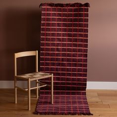 a chair sitting next to a blanket on top of a wooden floor in front of a brown wall