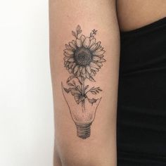 a sunflower in a light bulb tattoo on the arm