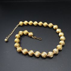 "*Description: This is a beautiful Napier gold tone beaded necklace which is strung on chain from the 1950s. The 12mm beads have a swirling textured finish with smaller spacer beads on the extension chain. This necklace is signed on the hook \"Napier\". This is a great statement necklace for any outfit or make a wonderful vintage jewelry gift. *Approximate Measurements: Length - 17 Inches, Width - 1/2 Inch *Condition: Great vintage condition. Will see signs of wear under magnification. *Hallmark Vintage Yellow Gold Polished Bead Necklace, Vintage Gold Single Strand Jewelry, Vintage Yellow Gold Necklaces With Polished Beads, Vintage Yellow Gold Necklace With Polished Beads, Vintage Yellow Gold Beaded Necklaces With Round Beads, Vintage Yellow Gold Single Strand Necklace, Vintage Gold Beaded Jewelry, Vintage Gold Jewelry With Polished Beads, Vintage Gold Beads Jewelry For Formal Events