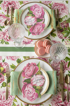 the table is set with pink flowers and place settings