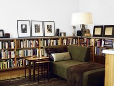 a living room filled with lots of books on top of a book shelf next to a couch