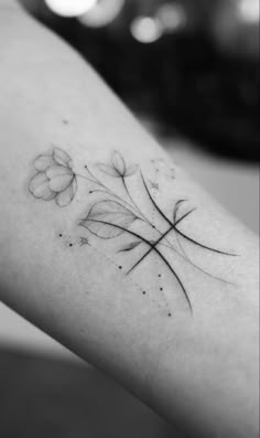 a black and white photo of a flower tattoo on the left arm, which has four petals in it