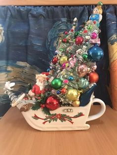 a christmas tree is sitting in a sleigh with ornaments on the top and bottom