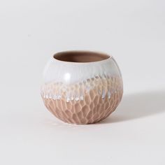 a white and brown vase sitting on top of a table