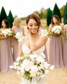 the bridesmaids are holding their bouquets in front of her face and smiling