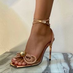 Named After The Queen Of Diamonds, Elizabeth Taylor. Featuring A Sparkling Double Bow And Over Sized Gem Centerpiece. Mirrored Rose Gold Insole And Heel. Double Ankle Strap And Stiletto Heel. Composition: 4.5” Covered Heel Upper: Rose Gold Metallic Pu Sole: Rubber 100% Vegan, Animal And Cruelty-Free Features A Buckle Fastening Ankle Strap Imported Rose Gold Open Toe Heels With 4-inch Heel, Feminine High Heels For Night Out, Feminine High Heel Heels For Night Out, Rose Gold 4-inch Heels For Formal Occasions, Rose Gold Pointed Toe Heels For Party, Elegant Pink Heels For Night Out, Glamorous Party Heels With Sculpted Heel, Feminine Fitted Sandals For Party, Glamorous Ankle Strap Heels For Cocktail