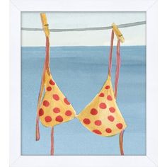 two bras hanging on a clothes line in front of the ocean, one with red polka dots