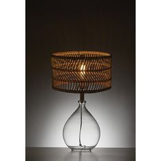 a table lamp with a glass base and wicker lampshade on the top