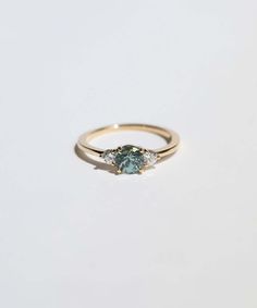 a yellow gold ring with an aqua blue diamond and three diamonds on the side, set in