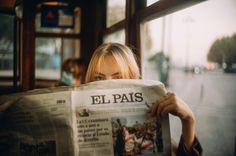 a woman reading a newspaper in front of a window on a bus with the caption el pais