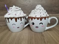 two coffee mugs with whipped cream and chocolate icing on them, one has eyes