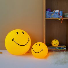 two yellow smiley faces sitting next to each other in front of a bookshelf