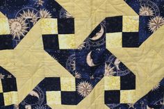 a blue and yellow quilt with sun and moon designs on the sides, along with stars