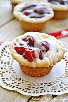 two small pastries on a doily with white icing and cranberry toppings