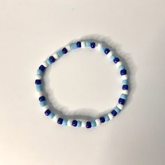 a blue and white beaded bracelet on a white surface with a small black heart charm