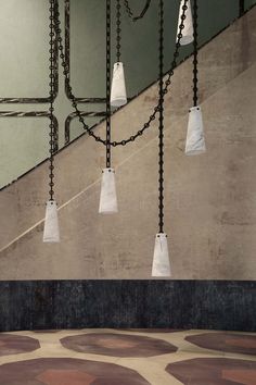 a bunch of lights that are hanging from some kind of chain on a wall in a building