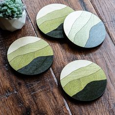 three wooden coasters sitting on top of a table next to a potted plant