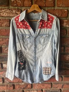 a denim shirt with patches on the front and back, hanging against a brick wall