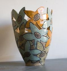 a ceramic vase sitting on top of a table next to a white wall and floor