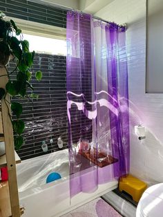 a purple shower curtain in a bathroom next to a toilet