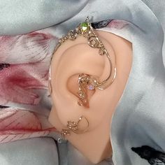 Discover the magic of the forest with this exquisite fairy ear cuff. Crafted from sterling silver, this delicate piece features a shimmering Austrian crystal at its center, surrounded by intricate swirls and curves. A natural pearl adds a touch of elegance and a timeless allure. Perfect for adding a touch of whimsy to your everyday look or as a special gift for the fairy-loving friend in your life.  Materials:  * Sterling silver  * Austrian crystal  * Natural pearl Care Instructions:  * To maintain the luster of your jewelry, gently wipe it with a soft cloth after each wear.  * Avoid contact with harsh chemicals and store in a cool, dry place. Additional Ideas:  * Consider custom options, such as different crystal colors or pearl sizes.  * Work with designer to create a customized matching Silver Fairy, Fairy Ears, Crystal Colors, Makeup Accesories, Fairy Jewelry, Wrap Earrings, Natural Pearl, Cuff Earrings, Matching Necklaces