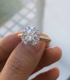 a close up of a person's hand holding an engagement ring