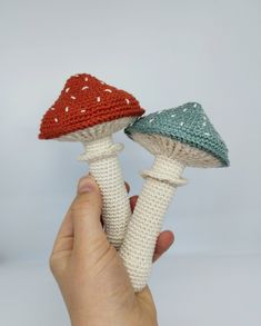 two crocheted mushrooms are being held up