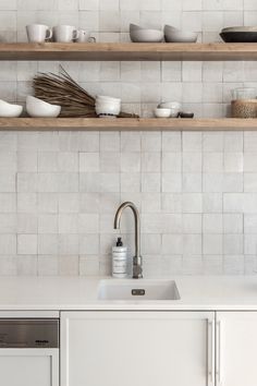 a kitchen with white tile and wooden shelves