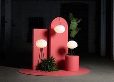 a pink sculpture sitting next to a plant on top of a red circular floor mat