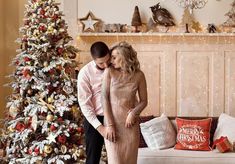 a man and woman standing in front of a christmas tree