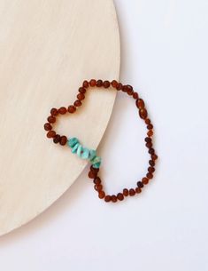 a small beaded necklace on top of a wooden disc with a turquoise and brown bead