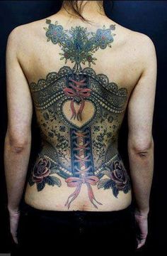 the back of a woman's body with tattoos and flowers on her chest,