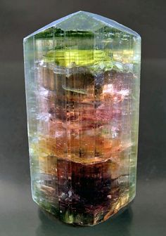 a multicolored glass vase sitting on top of a table next to a black surface