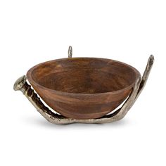 a wooden bowl sitting on top of a white table next to a metal bird figurine