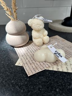 a white teddy bear sitting on top of a piece of paper next to a vase