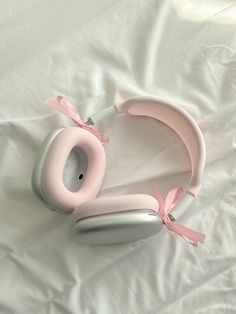 a pair of pink headphones laying on top of a white bed sheet covered in sheets