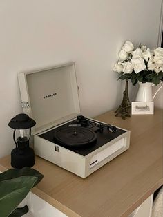 a record player sitting on top of a table next to a vase with white flowers