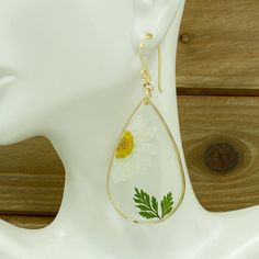 Original real flower earrings made real daisy and leaf, encased in resin in the teardrop gold plated. A truly special and beautiful way to bring nature with you wherever you go! The earrings are LIGHTWEIGHT! Dainty gift for her. When buying my jewelry you may be sure it is original and truly one of a kind ♥ I T E M ~ D E T A I L S: * Lenght: 2.7 inch * Wide: 1.2 inch * Drop length: 1.9 inch * Materials: UV resin, real pressed flower, gold filled wire, gold plated, nickel free. ♥ GIFT IT Jewelry White Teardrop Earrings, Gold Teardrop Earrings For Summer, Gold Birth Flower Jewelry For Summer, White Pressed Flowers Earrings, White Earrings With Pressed Flowers, White Pressed Flower Drop Earrings, White Pressed Flowers Drop Earrings, Teardrop Jewelry With Pressed Flowers, White Drop Earrings With Pressed Flowers