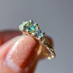 a close up of a person's hand holding a ring with two stones on it