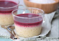 two glasses filled with food sitting on top of a table next to bowls and spoons