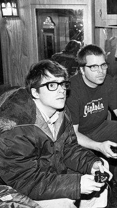 black and white photograph of two men sitting on a train holding game controllers in their hands