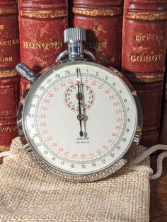 an old stopwatch sitting in front of some books