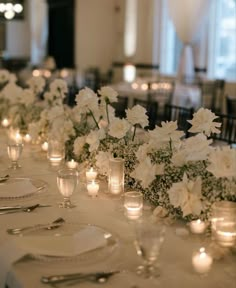 white flowers and candles are lined up on the table for a formal dinner or reception